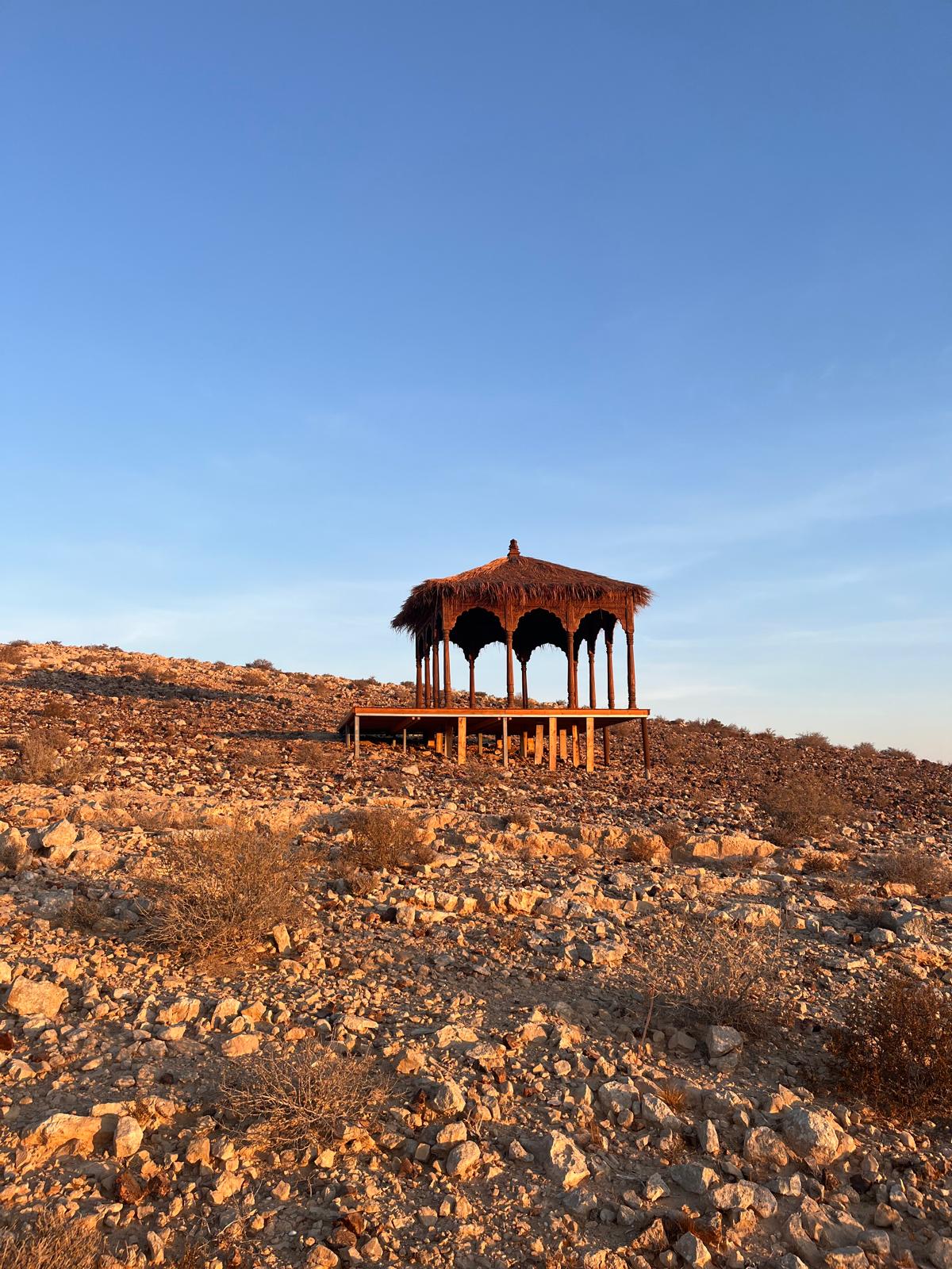 Un pavillon posé dans le désert, à la lumière du soir